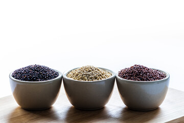 Red, black and white quinoa seeds on wooden background. Vegetarian food
