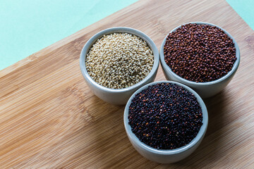 Red, black and white quinoa seeds on wooden background. Vegetarian food