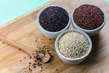 Red, black and white quinoa seeds on wooden background. Vegetarian food