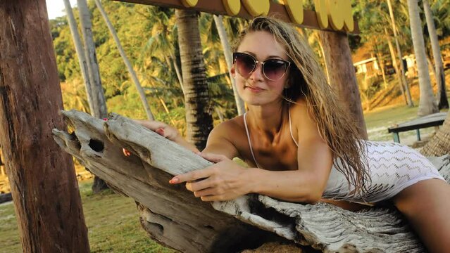 The sexy vibrant young lady is posing on a tree. The woman is having fun on an island vacation.