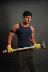 The sexy construction man holds a sledgehammer in his hands. 