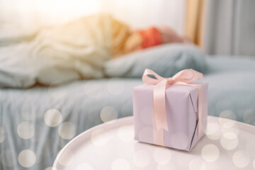 Women's day. Woman sleeping in bed near gift box. Christmas, New Year, Valentine's Day and birthday concept