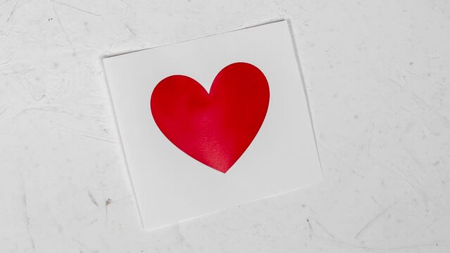 Unfolded paper with a heart. A red heart appears on a sheet of paper. Valentine's day, love concept. Stop motion.
