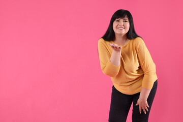 Obraz premium Beautiful overweight mature woman with charming smile on pink background. Space for text
