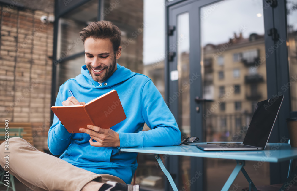 Poster cheerful male writing education information while e learning in sidewalk cafe with good wifi connect