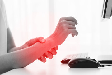 Woman working in office with a carpal tunnel syndrome or wrist joint inflammation