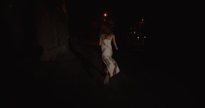 Scared woman in a nightgown runs down the street, running away from home.