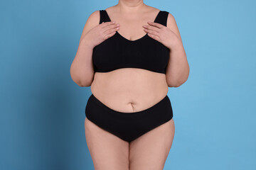 Fototapeta premium Overweight woman in underwear on light blue background, closeup