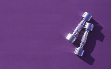 Purple yoga mat with metal chromed dumbbells. 