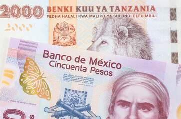 A macro image of a pink, plastic fifty peso bank note from Mexico paired up with a orange and white...