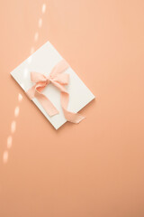 Wrapped gift with pink bow on pink background with white space