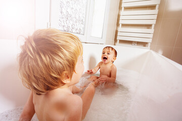 Obraz na płótnie Canvas Happy little baby boy play in the bath with sister
