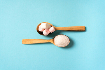 Marshmallow and sugar on opposite wooden spoons. Diabetes concept. Top view.