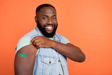 Photo of charming guy dressed jeans waistcoat empty space showing sticky plaster isolated orange color background