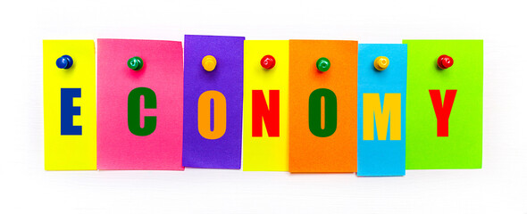 On a white background, buttons are used to fix bright multi-colored strips of paper with the text ECONOMY
