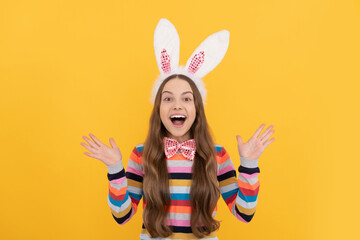 amazed easter girl in bunny ears and bow tie on yellow background