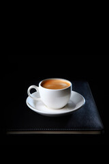 A cup of coffee is on a notepad for notes.Top view.Business breakfast.Food and drinks.Coffee break. Space for copying.Flat lay.Vertical photo.
