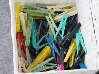 Photo of different colored clothes pegs in a white basket