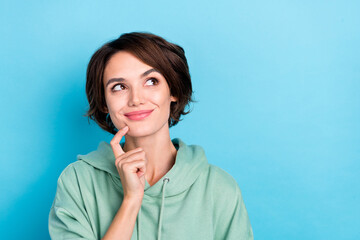Photo of dreamy thoughtful lady dressed green pullover finger chin looking empty space isolated blue color background