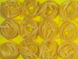 Pasta nest on a yellow background. Noodle type. Culinary background. Background from noodles.Pasta on the table. Unprepared product.  Dough products
