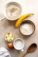Ingredients for preparing banana cookies and dough on color wooden background