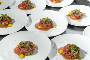 Tartarus from young calf with avocado, garnished with nori leaves and parsley. Many plates are ready to be served to the guests.