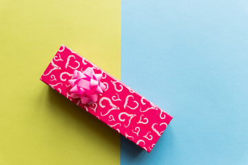 Fototapeta na wymiar red gift box with red heart, with pink bow on colorful background. Holiday web banner. Top view.minimal style, greeting card template. copy space