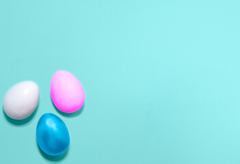 Eggs colored with violet, pink and blue colors in a corner on a blue background. Flat lay. Easter holiday concept. Copy space for text, mock up. Banner.