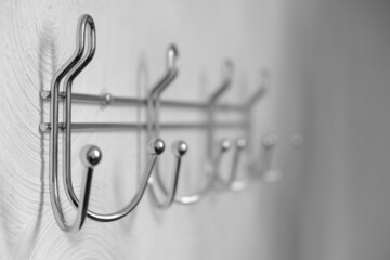 Fototapeta premium Extremely close-up metal coat hooks on white wall, selective focus