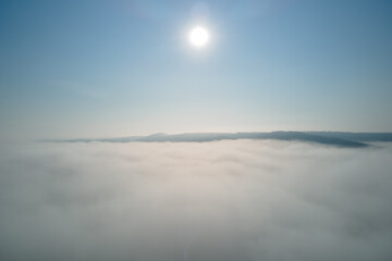 Aerial view from high altitude of earth covered with white puffy cumulus clouds on sunny day