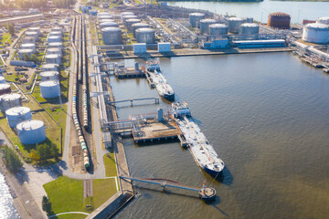 Aerial view large port with railway infrastructure for the delivery of bulk cargo by sea, loading oil using a pump station in ship tanker for transportation and delivery.