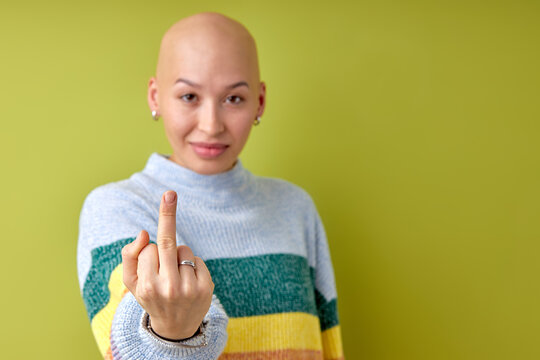 Young beautiful bald caucasian woman wearing casual shirt standing over isolated green background Showing middle finger, impolite and rude fuck off expression. hairless caucasian model