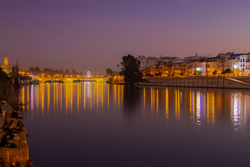Fototapeta na wymiar Sunset over the river Guadalquivir in downtown Seville with amazing colors in the sky and a view on the riverside of the Triana neighbourhood.