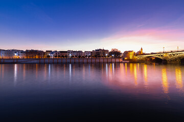 Fototapeta na wymiar Sunset over the river Guadalquivir in downtown Seville with amazing colors in the sky and a view on the riverside of the Triana neighbourhood.