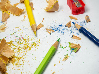School supplies. Pencil sharpening.   Multicolored pencils on a white background. Wood shavings....