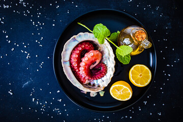 Fried octopus and vegetables on black wooden table
