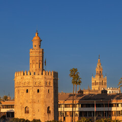 Fototapeta na wymiar The skyline of Seville with a view on the iconic golden tower on the quayside of the rivier Guadalquivir and in the distance the Giralda tower during the golden hour