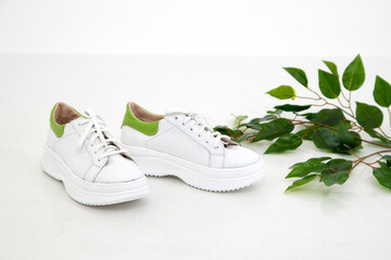 White women sneakers in the studio on white background. Fashion shooting for a catalog or store indoors
