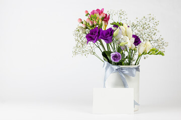 Beautiful Spring, summer flowers in vintage ceramic vase with ribbon, and Blank greeting card on white background.  Mock up, empty copy space.
