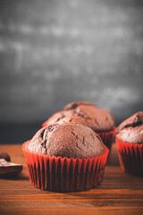 Homemade chocolate muffins or cupcakes on a wooden table and dark background