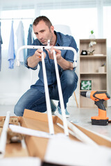 man assembly furniture from box with instruction on white paper