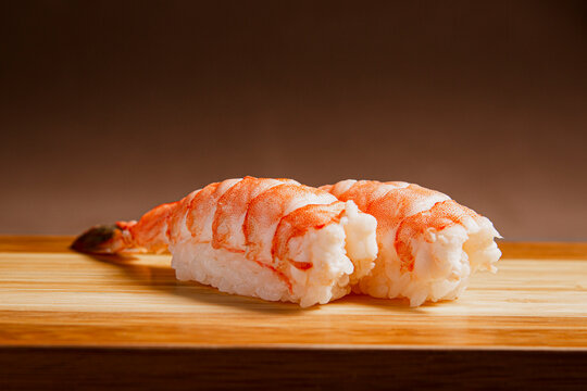 Sushi freshly prepared. Japanese food, sushi roll of shrimp in a wooden background. Fish and crustaceans slices. Front view with Copy Space.