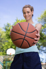 happy female athlete standing with basketball