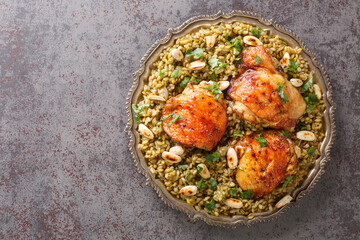 Lebanese chicken served on a bed of freekeh fire-dried green wheat with a garnish of toasted nuts closeup on the table. Horizontal top view from above - obrazy, fototapety, plakaty