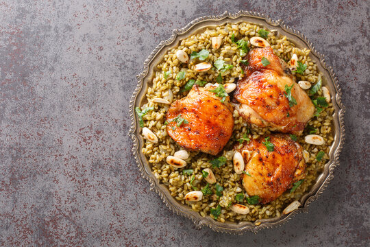 Lebanese chicken served on a bed of freekeh fire-dried green wheat with a garnish of toasted nuts closeup on the table. Horizontal top view from above