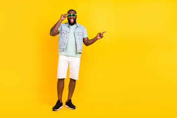 Fototapeta premium Full length body size view of handsome trendy cheery guy showing copy space isolated over bright yellow color background