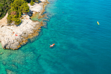 Top view of sportsmen or tourists kayaking in the turquoise transparent blue water of Adriatic sea rocky shore. Summer leisure activity in the canoe. 