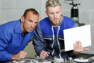 workers in blue overall checking laptop