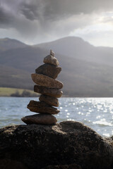 montículo de piedras en paisaje de agua y montañas