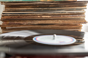 A Stack Of Vinyl Record Albums Rests Beside A Vinyl Record On A Turntable.